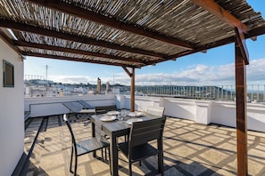 A rooftop terrace with a table set for dining, a pergola overhead, and a cityscape view. - La Terrazza tra Mare e Cielo by Wonderful Italy (Ostuni)