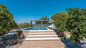 A swimming pool with steps leading up to it, surrounded by greenery and a clear blue sky. - Holiday Home 'Casa Rural Adalid' with Pool, Garden, Terrace & Wi-Fi (La Puebla de Cazalla)