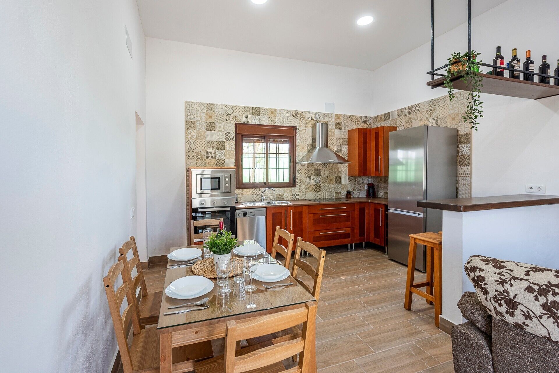 A compact kitchen with a dining area, wooden cabinets, a built-in oven, and a refrigerator.