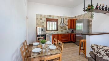 A compact kitchen with a dining area, wooden cabinets, a built-in oven, and a refrigerator.