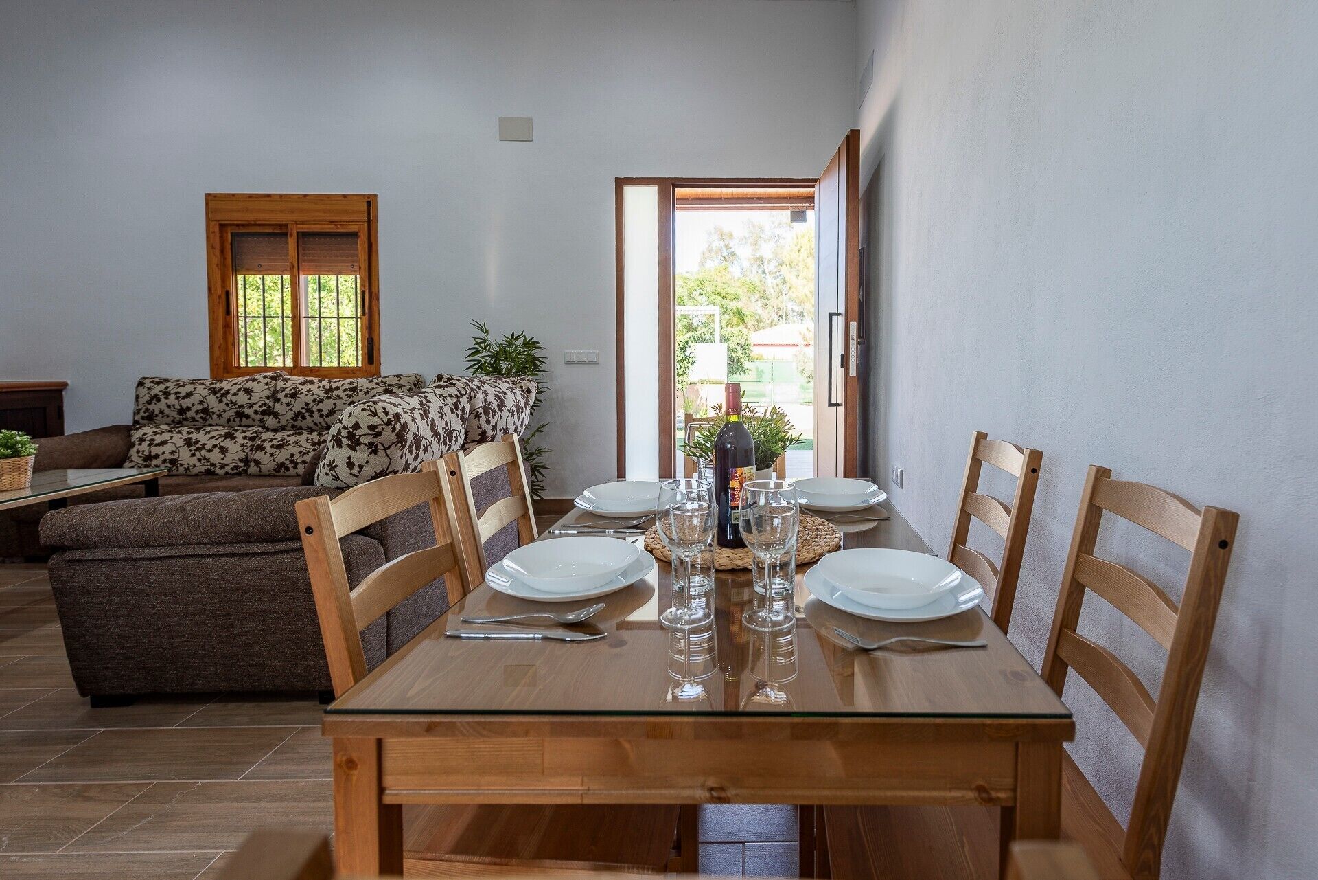 Un coin repas avec une table en bois dressée pour quatre personnes, entourée de chaises en bois.