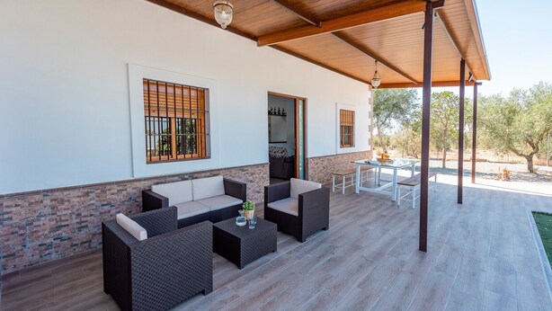 An outdoor patio with wicker furniture, a glass table, and a view of the surrounding landscape. - Holiday Home 'Casa Rural Adalid' with Pool, Garden, Terrace & Wi-Fi (La Puebla de Cazalla)