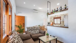 A living room with a sofa, a coffee table, and a kitchen area with a microwave. - Holiday Home 'Casa Rural Adalid' with Pool, Garden, Terrace & Wi-Fi (La Puebla de Cazalla)