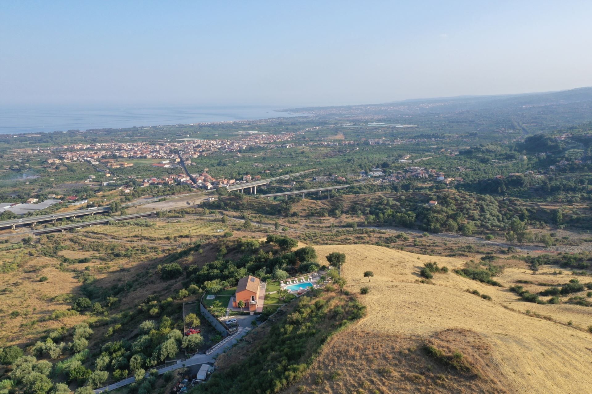 Vue aérienne d’une ville côtière, avec une église imposante, un pont et un espace piscine.