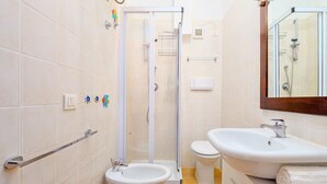 Un baño con ducha, inodoro, lavabo y barras de apoyo.