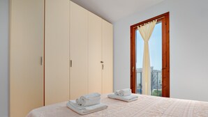 Un dormitorio con cama, armario y ventana con cortina.