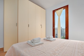 Une chambre à coucher avec un lit, une armoire et une fenêtre avec un rideau.