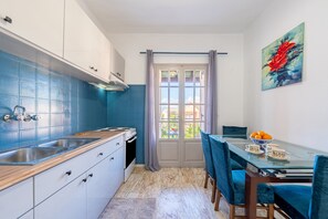 Eine Küche mit blauen Fliesen, einem Esstisch mit Stühlen und einem Fenster mit Vorhängen.