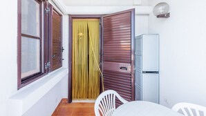 Una habitación con una puerta corredera, una silla blanca, una mesa y un mueble blanco pequeño.