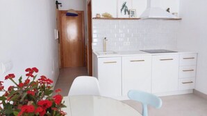 Una cocina moderna con armarios blancos, un lavamanos y un comedor con mesa y sillas.