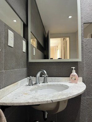 A bathroom with a marble sink, a modern faucet, and a hand soap dispenser. - Spacious and light apartment- Pto Madero and Centro

 (Buenos Aires)