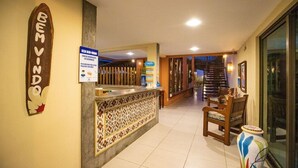 A reception area with a reception desk, a sign reading "Bem Vindo", and a staircase leading to upper floors.