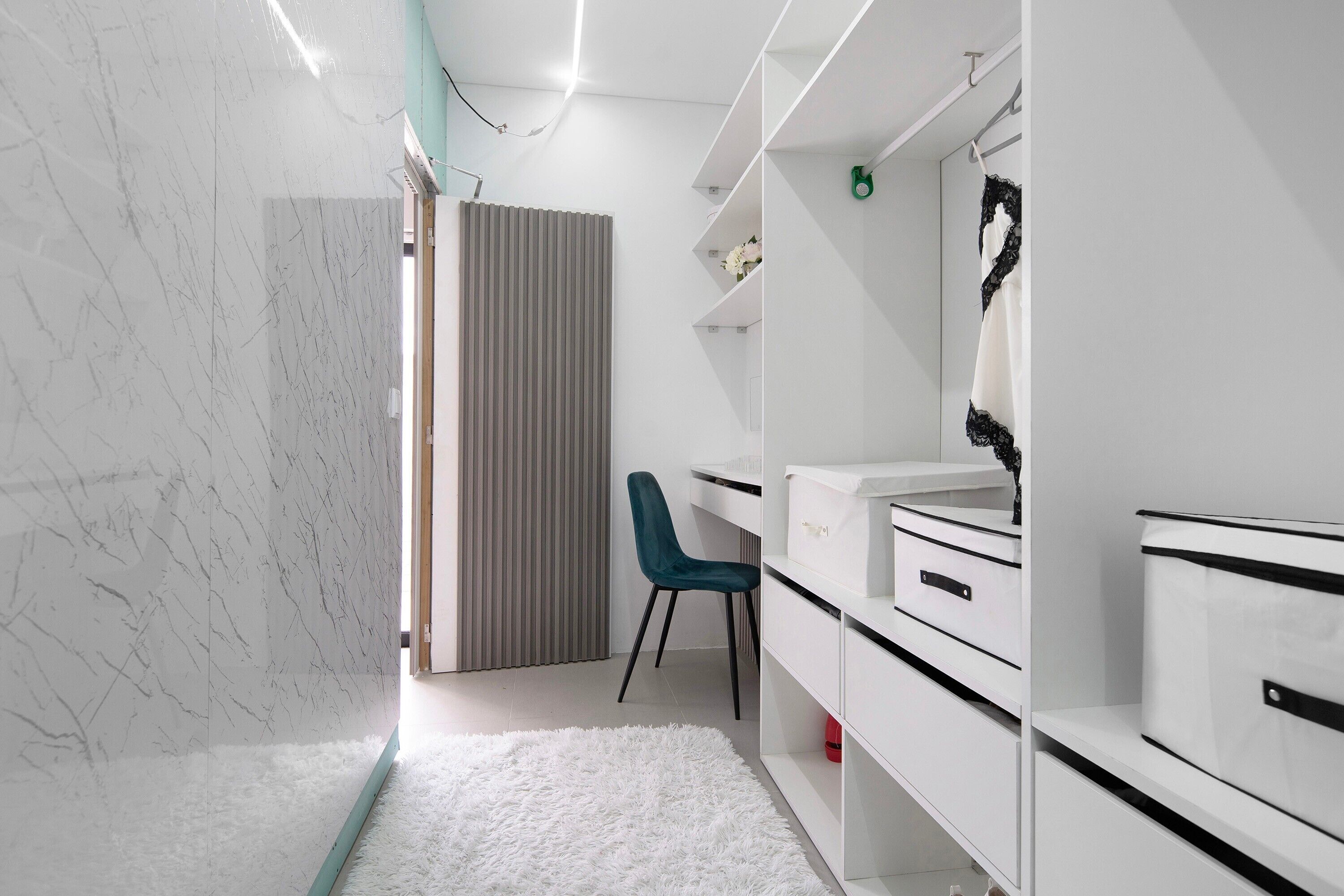 Un baño moderno con un tocador blanco, un espejo y una silla.