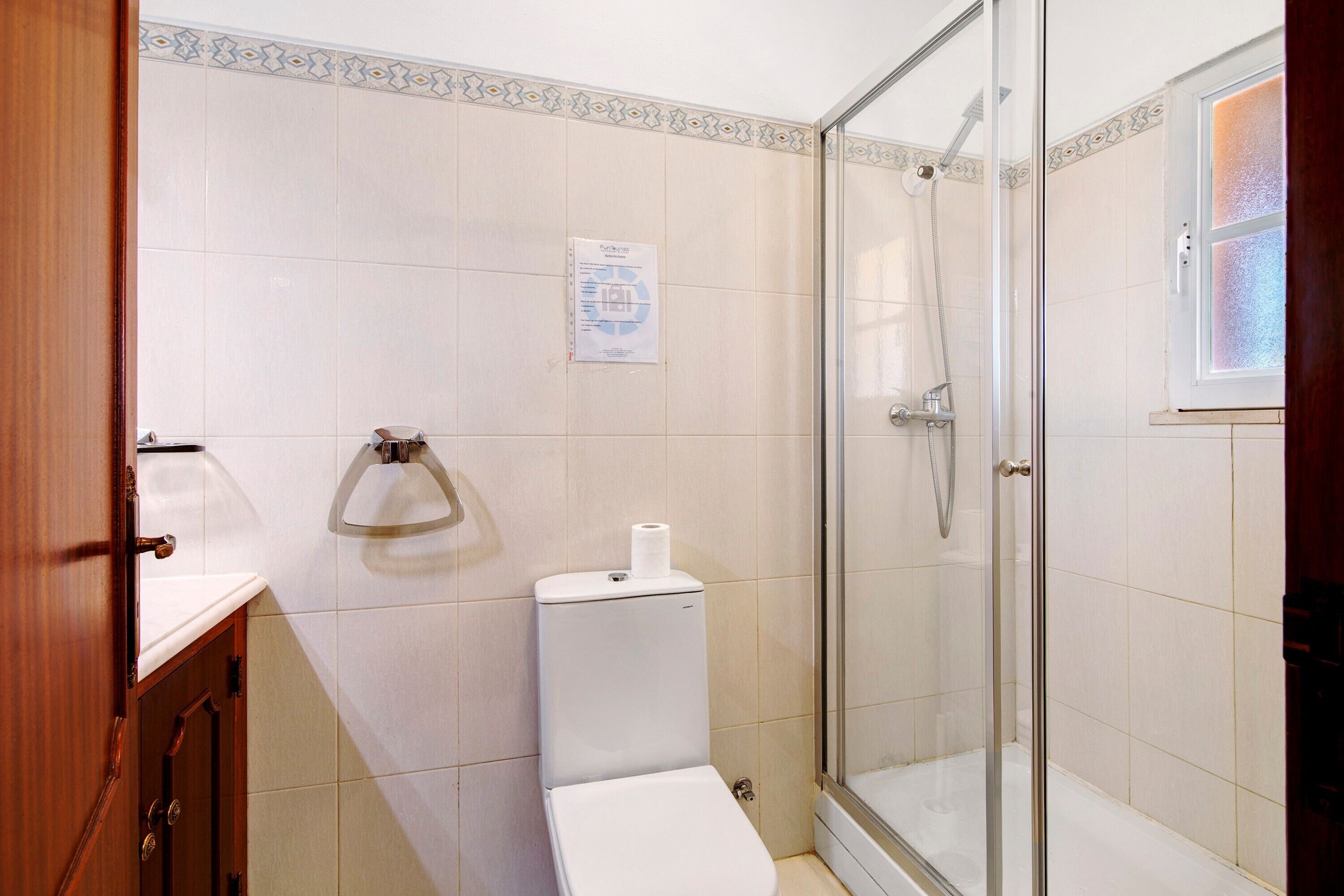A bathroom with a toilet, a shower, and a glass door.
