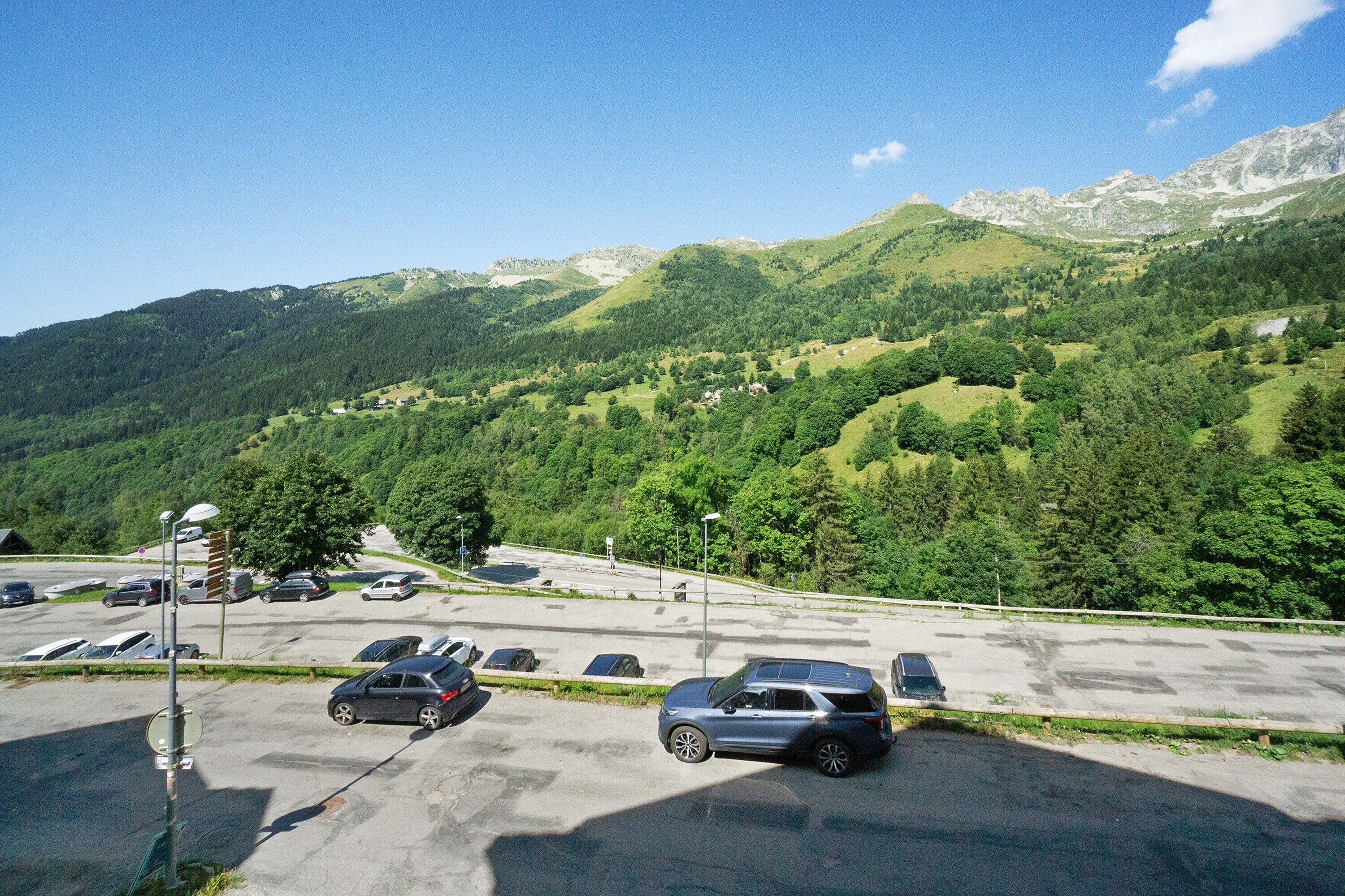 A parking lot with cars and a mountain landscape in the background.