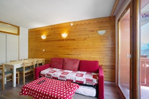 Ein Zimmer mit Holzwänden, einem roten Sofa, einem kleinen Tisch und zwei Wandleuchten.