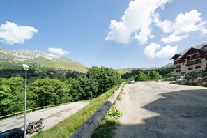 Eine asphaltierte Straße mit Holzlattenzaun, einem abgestellten Motorrad und einem Gebäude mit Balkonen.