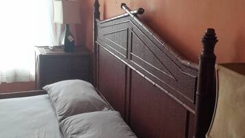 Un dormitorio con cama, mesita de noche, lámpara y aire acondicionado.