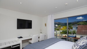 Une chambre d’hôtel moderne dotée d’un grand lit, d’un bureau avec une chaise, d’une télévision et offrant une vue sur les montagnes.