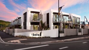 Un hôtel moderne, reconnaissable à son grand panneau représentant des voiles, qui se distingue par son architecture originale, avec de nombreux balcons et une vue sur le front de mer.