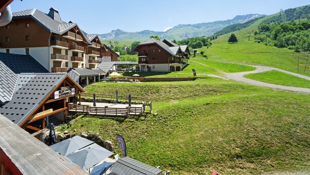 Ein Bergresort mit Chalet-Gebäuden, einer Holzterrasse und freiem Blick auf die umliegenden Hügel.
