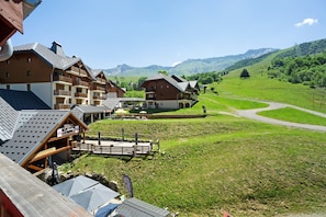 Une station de montagne avec des bâtiments de style chalet, une terrasse en bois et une vue dégagée sur les collines environnantes.