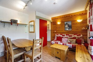 Un interior de madera con una mesa de comedor, sillas, un banco y un sofá con una colcha acolchada.