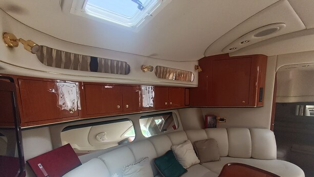 A compact, well-lit interior with a sofa, cushioned seating, and wooden cabinets. - ALL EXCLUSIVE YACHT (Puerto Aventuras)