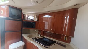 A compact kitchen with a microwave, stove, sink, and cabinets. - ALL EXCLUSIVE YACHT (Puerto Aventuras)