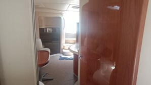 A narrow corridor leading to a bathroom with a wooden door and a sink. - ALL EXCLUSIVE YACHT (Puerto Aventuras)