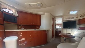 A compact RV interior with a kitchenette, a seating area, and a television. - ALL EXCLUSIVE YACHT (Puerto Aventuras)