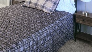Un dormitorio con cama, ventilador de techo, mesita de noche y lámpara.