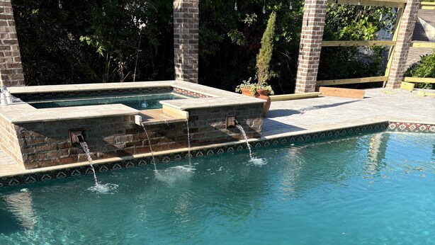 Una piscina limpida con bordo in pietra e un elemento decorativo a tema acqua.