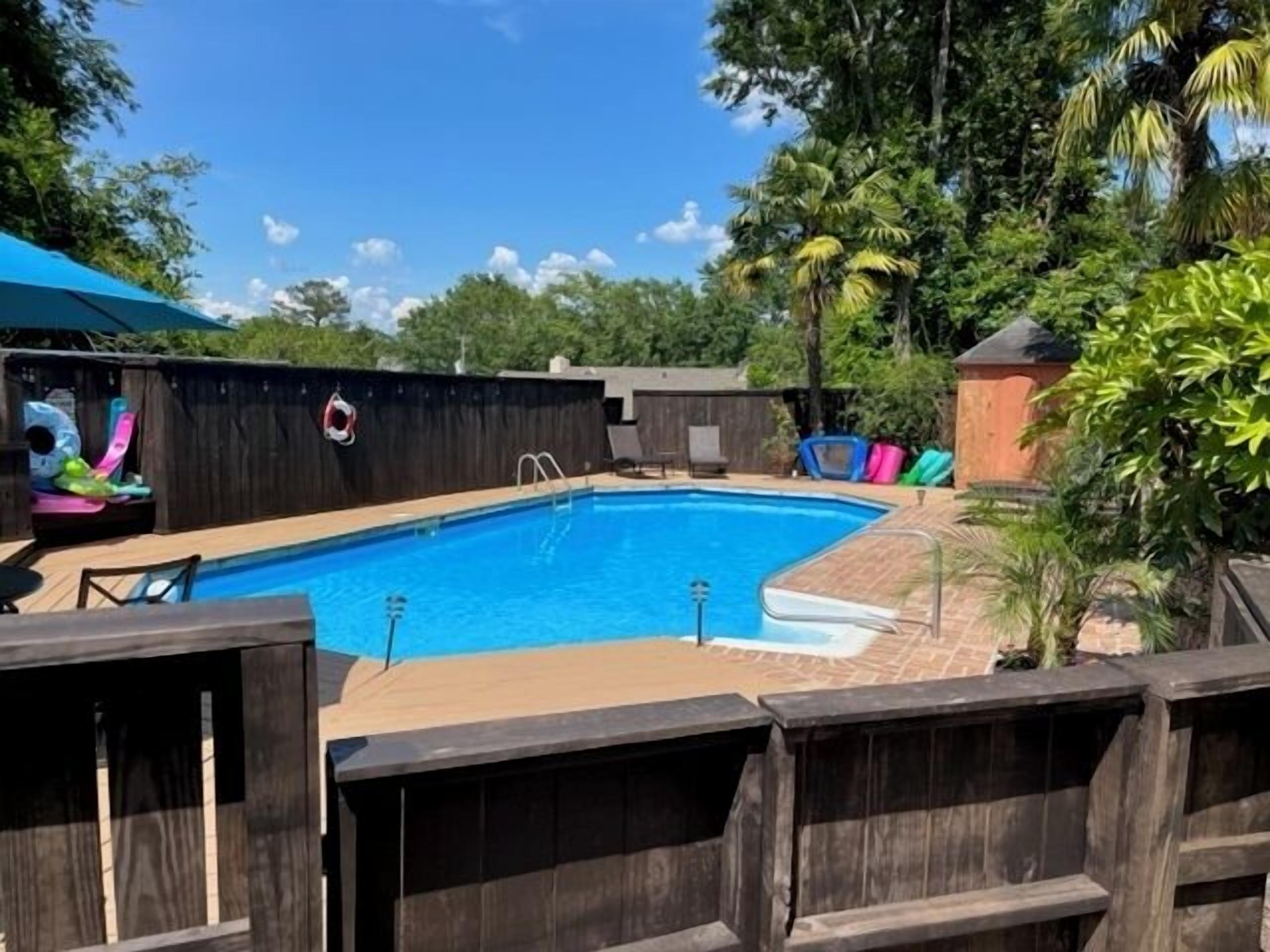 A rectangular swimming pool with a wooden deck and a lifeguard chair.