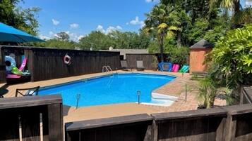 A rectangular swimming pool with a wooden deck and a lifeguard chair.