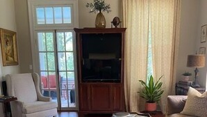 Un soggiorno con divano, poltrona, tavolino e televisore.