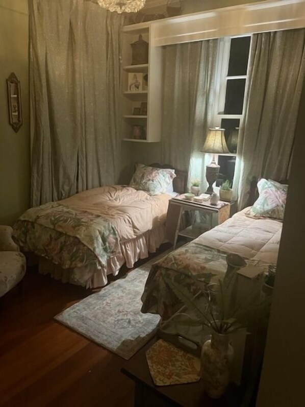 A bedroom with two beds, a nightstand, a lamp, and a window with curtains.