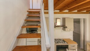Une cuisine équipée d’une cuisinière à gaz, de placards et d’un escalier en bois.