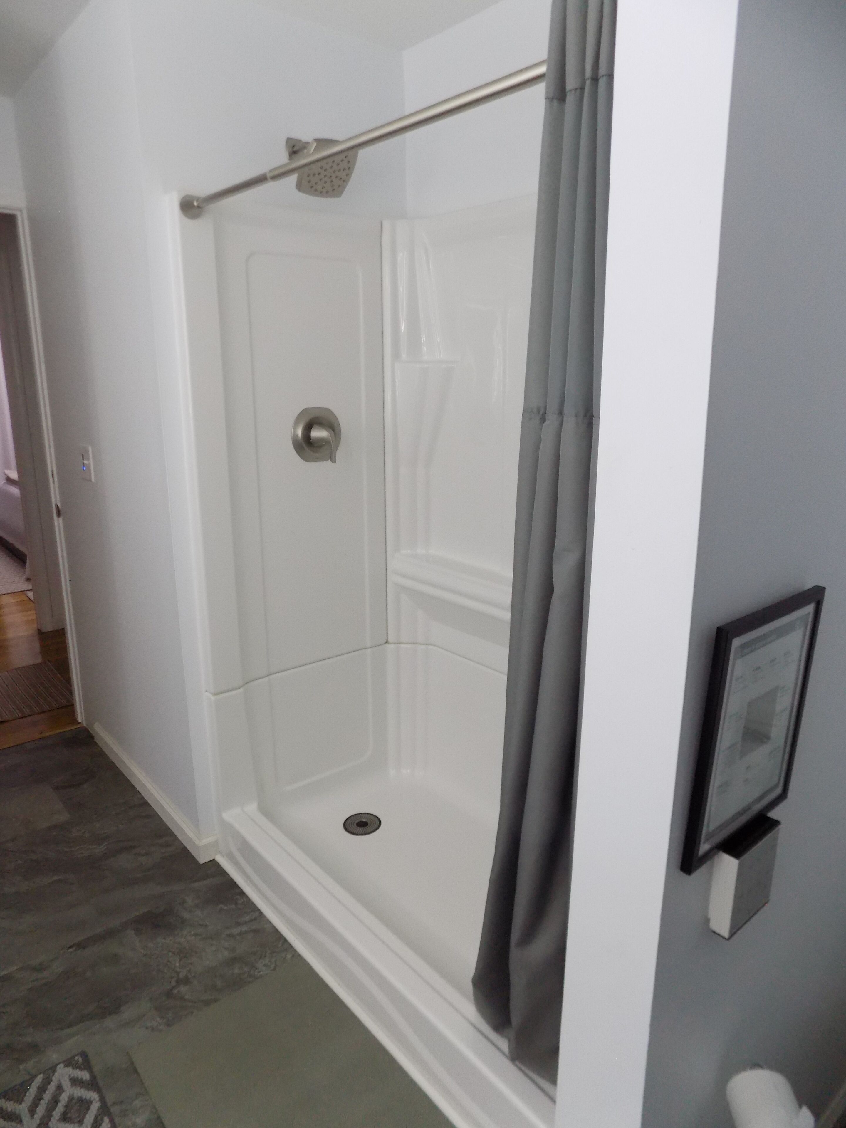 A walk-in shower with a glass door, a showerhead, and a curtain.