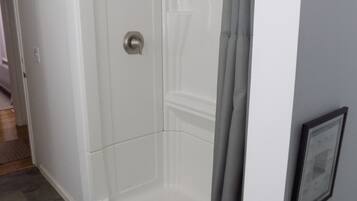 A walk-in shower with a glass door, a showerhead, and a curtain.