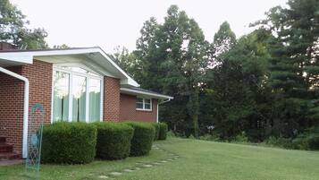 A brick house with a well-maintained lawn and a metal fence.