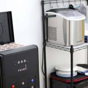 Una máquina de café PRIMO con panel de control, dispensador de agua y portacápsulas de café.