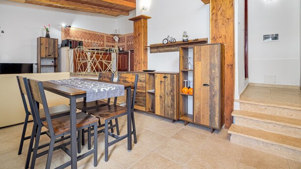 Eine Küche mit Holzschränken, einem Esstisch mit Stühlen und einer Treppe zu einer oberen Ebene.