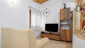 Ein Wohnzimmer mit einem beigefarbenen Sofa, einer Holztrennwand, einem Flachbildfernseher und einer Wanduhr.