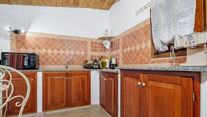 Eine Küche mit Holzausstattung, einer Mikrowelle, einem Spülbecken und einem Fenster mit Vorhängen.