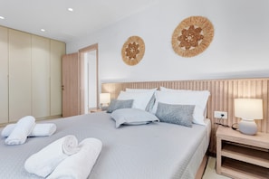 A neatly made bed with pillows, a bedside table with a lamp, and a wall with two decorative wall hangings.