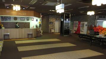 A reception area with a counter, a receptionist, and a wall with framed pictures.
