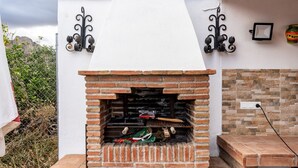 A brick-built outdoor grill with a white wall and decorative metal fixtures.