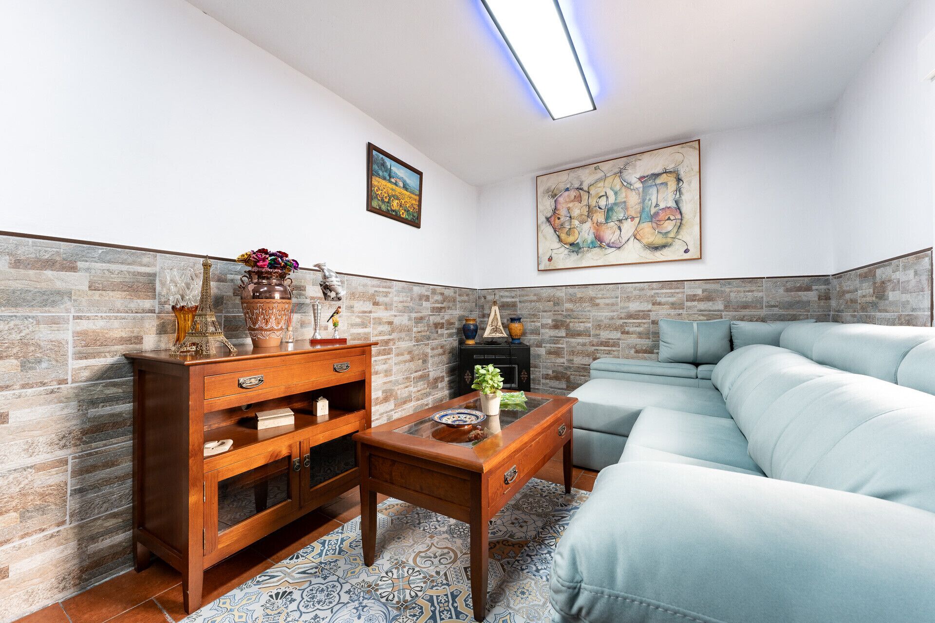 Een woonkamer met een hoekbank, een houten salontafel en een kast met decoratieve objecten.
