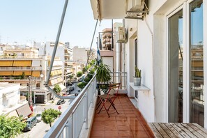A balcony with a view of the street, a potted plant, and a folding chair. - Apartment 'Dear Greece I Miss You' with Wi-Fi and Air Conditioning (Kallithea)